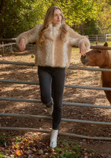 [Color: Natural] A front facing image of a blonde model wearing a tan brown stripe, dotted fur faux coat over a floral dress. Featuring a high collar, open front, and long sleeves. A cold weather style, perfect for any special occasion. 