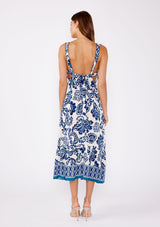 [Color: Vanilla/Navy] Brunette model wearing a blue and white floral tile print midi dress. A stunning dress with a flattering square neckline, sleeveless design, and an open tie back. A cute dress for vacation and warm weather occasions.