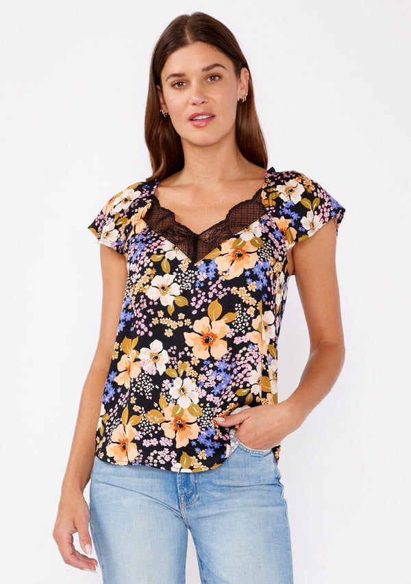 [Color: Black/Dusty Coral] A brunette woman wearing an all over floral print top with lace trim v neckline. A black and purple top with a ruffle trim detail and flutter short sleeves. The perfect day to night top styled with denim jeans.