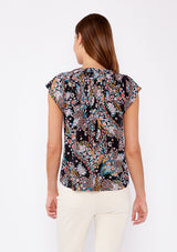 [Color: Black/Light Blue] An image of a brunette model wearing a multi color floral print bohemian top crafted from lightweight rayon fabric. With short cap sleeves, a split v neckline, and gathered details at the yoke. A summer to fall blouse perfect for casual outings. 