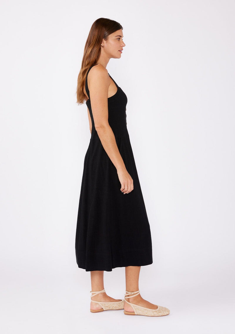 [Color: Black] A brunette model wearing a sleeveless midi dress with a functional button front and paired with tan ballet flats. A fit and flare dress with a sleeveless design and square neckline. A casual midi dress perfect for daytime activities and running errands.