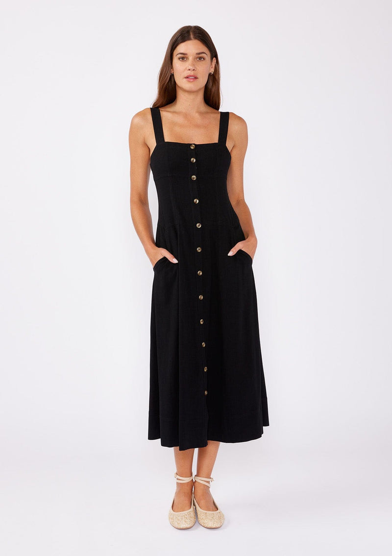 [Color: Black] A brunette model wearing a sleeveless midi dress with a functional button front and paired with tan ballet flats. A fit and flare dress with a sleeveless design and square neckline. A casual midi dress perfect for daytime activities and running errands.