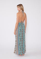 [Color: Natural/Tangerine] A back facing image of a blonde model wearing a sleeveless summer maxi dress in a bohemian mixed floral print, with gold metallic thread details. With a halter v neckline, an empire waist, and a strappy back with adjustable ties. 