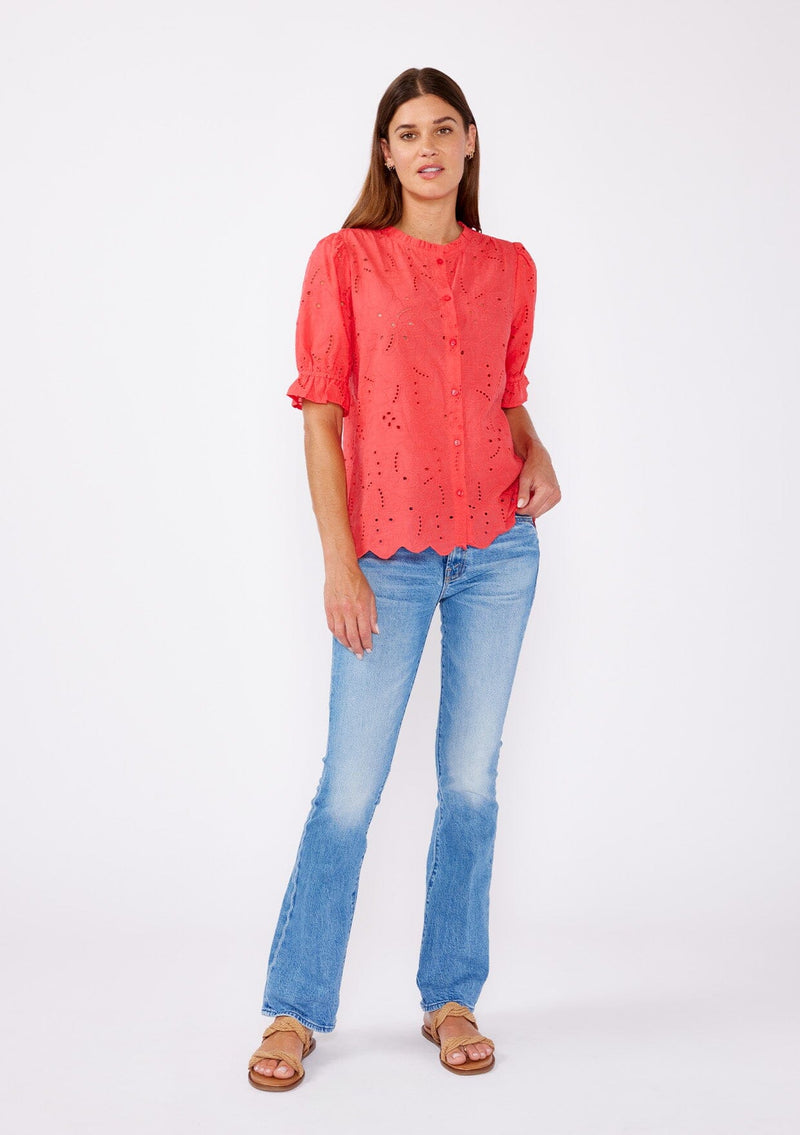 [Color: Coral] A brunette model wearing a coral orange top with a high round neckline, button front, and puff sleeves. Features a ruffled elastic cuff for added flair. A summer top with no lining for a comfortable breezy style for the summer.