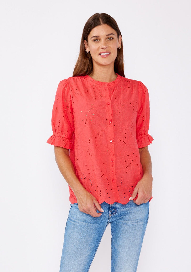 [Color: Coral] A brunette model wearing a coral orange top with a high round neckline, button front, and puff sleeves. Features a ruffled elastic cuff for added flair. A summer top with no lining for a comfortable breezy style for the summer. 