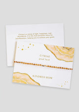 [Color: Citrine] An adjustable healing bracelet, crafted on a durable nylon cord with gold-plated hardware and orange natural gemstones. Designed by Kindred Row.