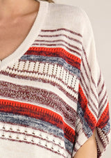 [Color: Cream/Red] A lightweight bohemian sweater poncho pullover top in a mixed stripe. With short sleeves, a v neckline, and a relaxed fit. 