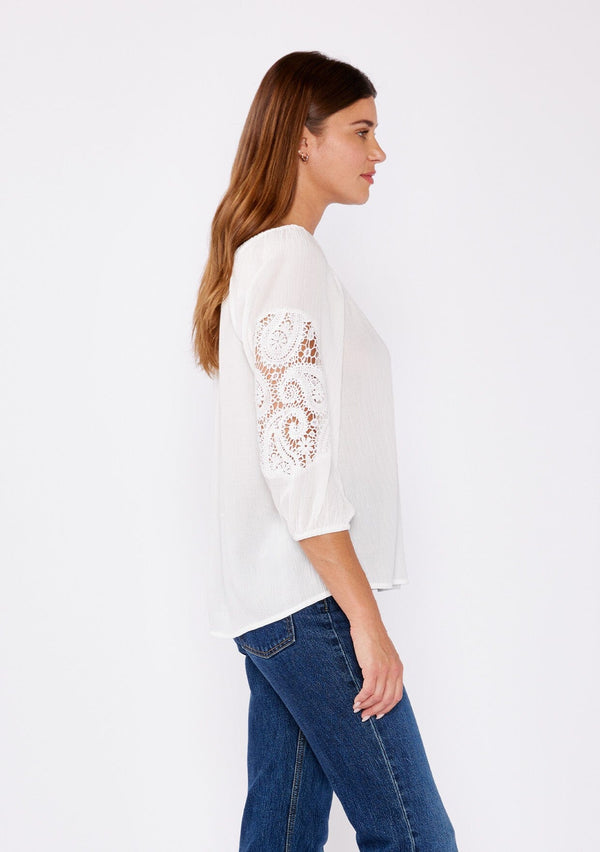 [Color: Off White] A brunette model wearing a casual white blouse with crochet lace detail. A summer top with an elastic neckline for on and off shoulder styling and three quarter length sleeves with elastic cuffs. A relaxed a flowy style perfect for casual outings.