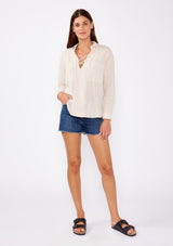 [Color: Sand] A relaxed fit blouse crafted from breathable textured cotton fabric. Features a collared neckline, lace up front, and long sleeves with button cuff closures. A daytime casual top for beach outings or running errands.