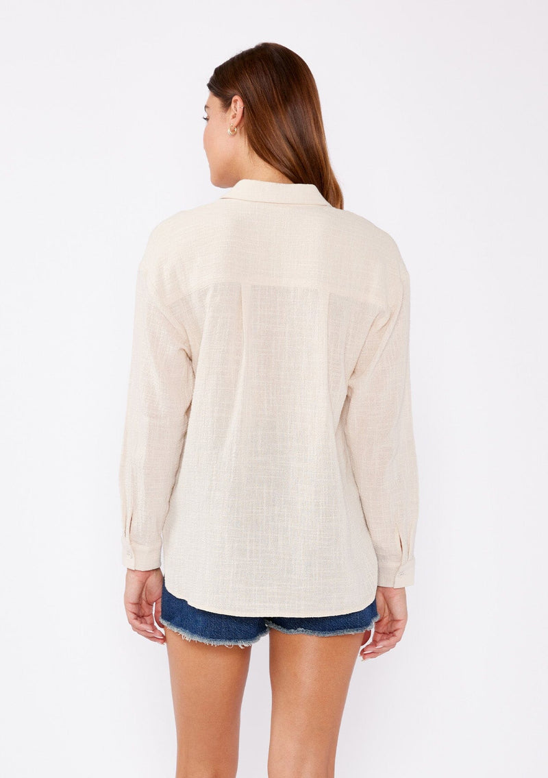 [Color: Sand] A relaxed fit blouse crafted from breathable textured cotton fabric. Features a collared neckline, lace up front, and long sleeves with button cuff closures. A daytime casual top for beach outings or running errands.