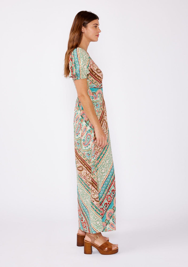 [Color: Jade/Natural] An image of a brunette model wearing a multi print bohemian maxi dress with brown heels for the fall season. A teal and green flowy dress with a v neckline, puff sleeves, and smocked back. A popular maxi dress for easy transition from summer to fall. 