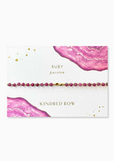 [Color: Ruby] An adjustable healing bracelet, crafted on a durable nylon cord with gold-plated hardware and purple gemstones. Designed by Kindred Row