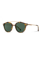 [Color: Dark Speckle] Clear Italian acetate sunglasses with contemporary round lens, metal brow bar, and wood accents. Framed with a tortoise, yellow and brown pattern.