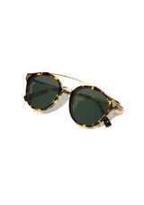 [Color: Dark Speckle] Clear Italian acetate sunglasses with contemporary round lens, metal brow bar, and wood accents. Framed with a tortoise, yellow and brown pattern. 