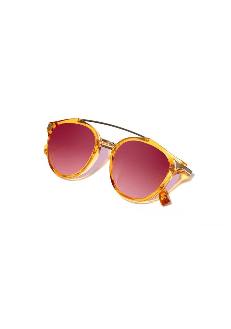 [Color: Tangerine] Clear Italian acetate sunglasses with contemporary round lens, metal brow bar, and wood accents. Orange frame accent with an ombre pink lenses. 