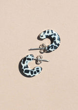 [Color: Speckle] A small ivory and black speckled acetate hoop earring. 