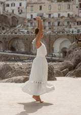 [Color: Off White] A brunette model wearing a white ultra bohemian maxi dress for vacation. This summer maxi dress features a halter neckline and a comfortable smocked waist. This dress is also embellished with intricate lace details and embroidered eyelet. The perfect style for brunch or a tropical vacation.