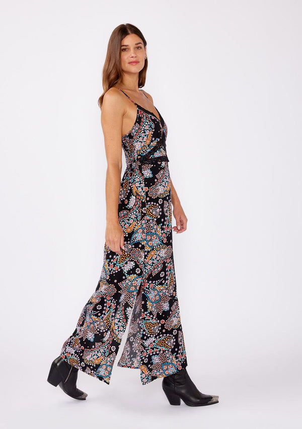 [Color: Black/Light Blue] A brunette model wearing a multi color floral print maxi dress with a flirty lace trim. An edgy bohemian maxi dress with a flattering v neckline, adjustable spaghetti straps, smocked back, and side slits. A sleeveless dress perfectly paired with boots or flats for the summer to fall season.
