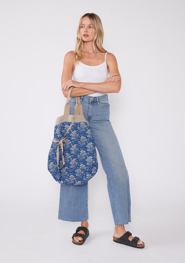 [Color: Natural/Blue/Off White] A reversible bohemian tote bag with double top handles, oversized grommets, an attached pouch with zip closure, and a tie closure. 