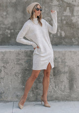 [Color: Silver] A woman standing outside wearing a mélange knit sweater dress. Featuring a mock neckline, long sleeves with contrast ribbed details, and an asymmetric front slit detail.