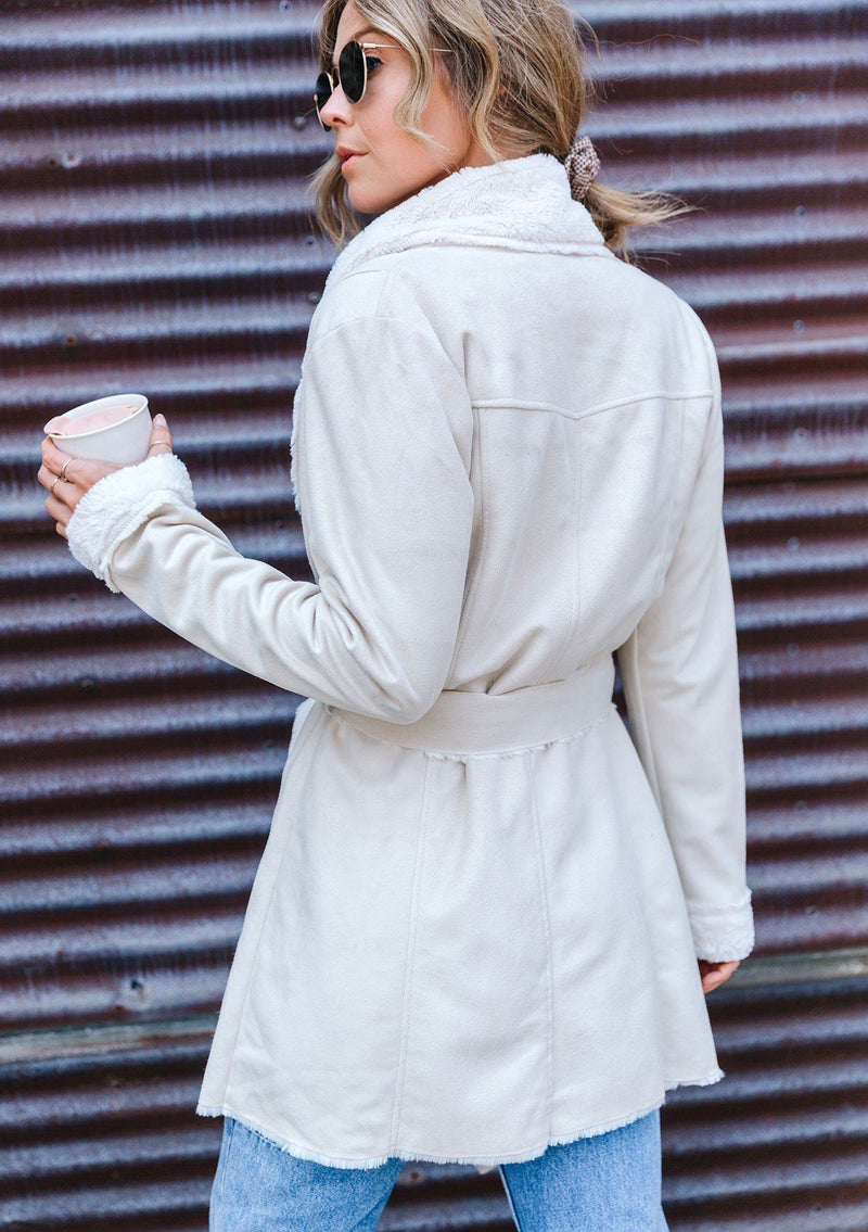 [Color: Winter White] A faux shearling coat in vegan suede. Featuring a cozy faux shearling interior and trim, a waist defining self tie belt, and essential side pockets. This timeless style is worn here with denim for a chic Fall look.