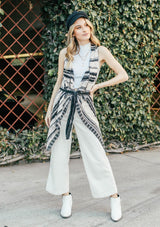 [Color: Cream/Black] Girl wearing a crochet striped knit vest with a shawl collar and a waist tie.