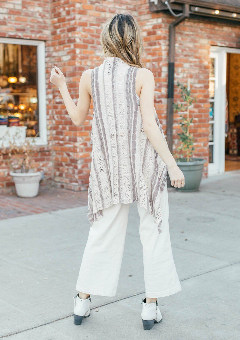 [Color: Cream/Mocha] Girl wearing a crochet striped knit vest with a shawl collar and a waist tie.