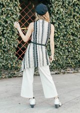 [Color: Cream/Black] Girl wearing a crochet striped knit vest with a shawl collar and a waist tie.