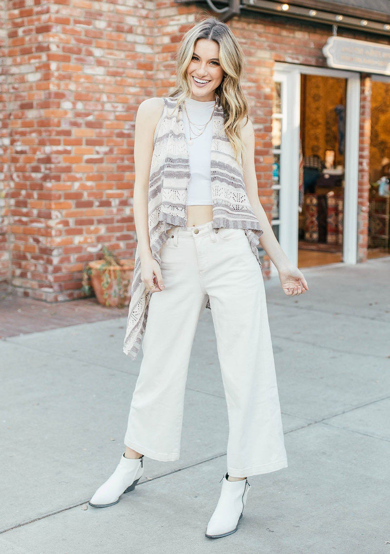 [Color: Cream/Mocha] Girl wearing a crochet striped knit vest with a shawl collar and a waist tie.