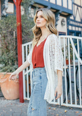 [Color: Off White] Girl wearing a white crochet short sleeve cocoon cardigan.