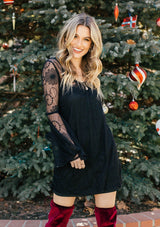 [Color: Black] A woman wearing a black mini dress with long lace bell sleeves and a scoop neckline. 