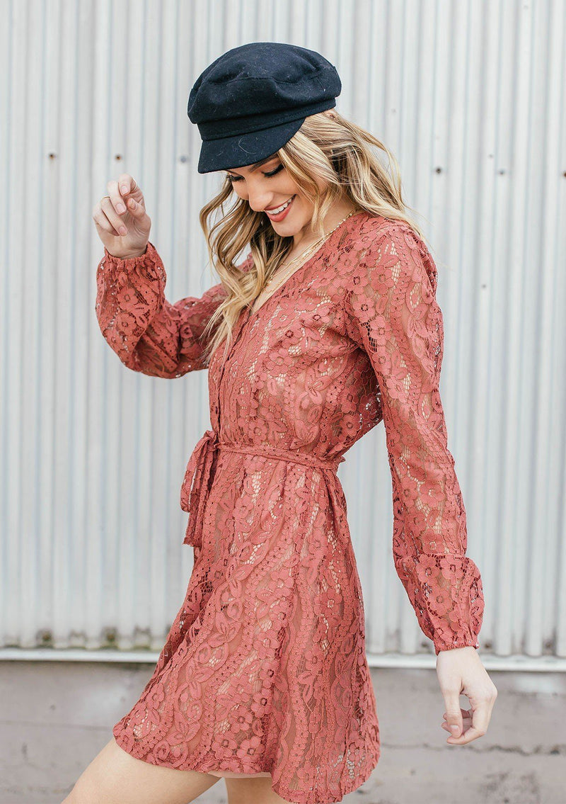 [Color: Spice] A lace mini dress featuring a flattering v neckline and waist defining self tie belt, and long sheer lace sleeves.