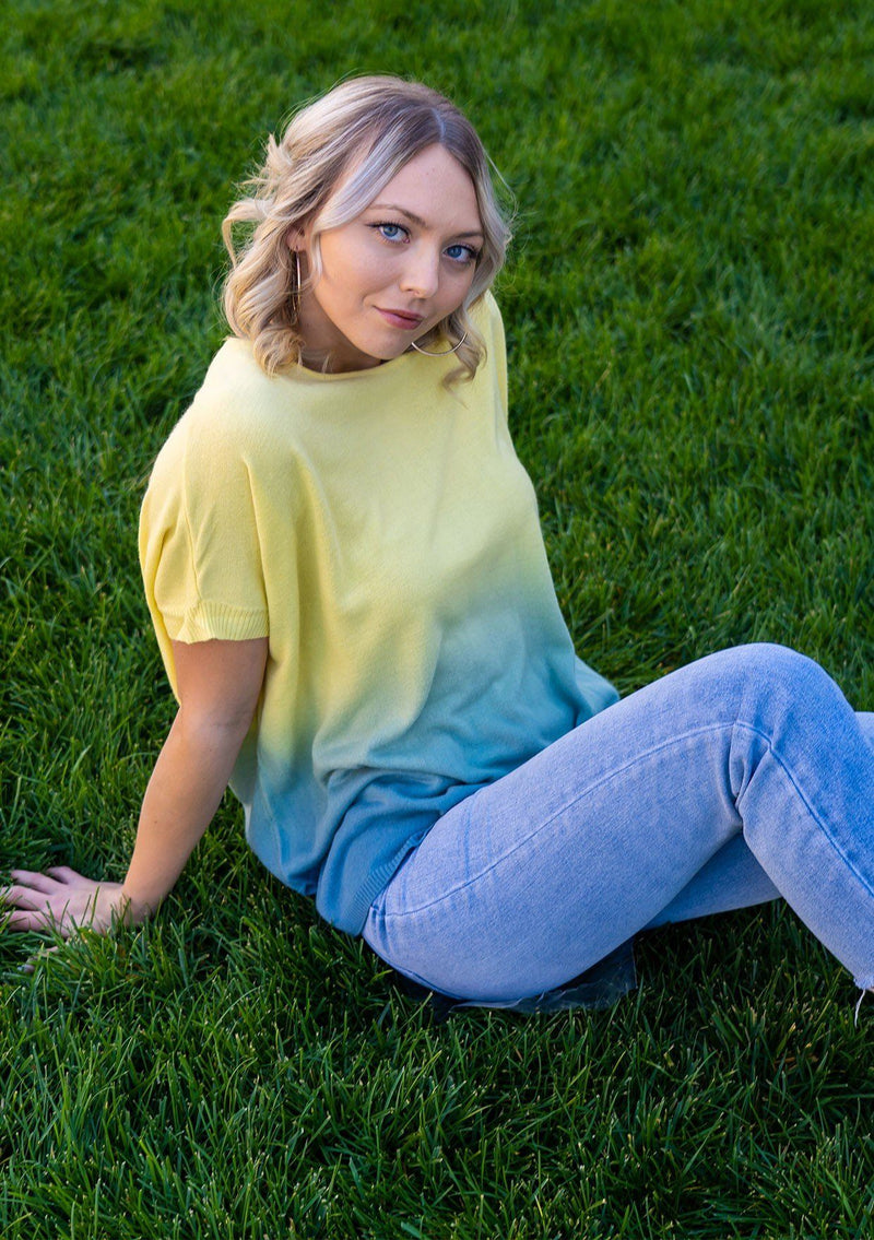 [Color: Lemon] A blond woman wearing an ombre tie dye sweater top. Features a scooped neckline, breezy side vents and front pockets. 