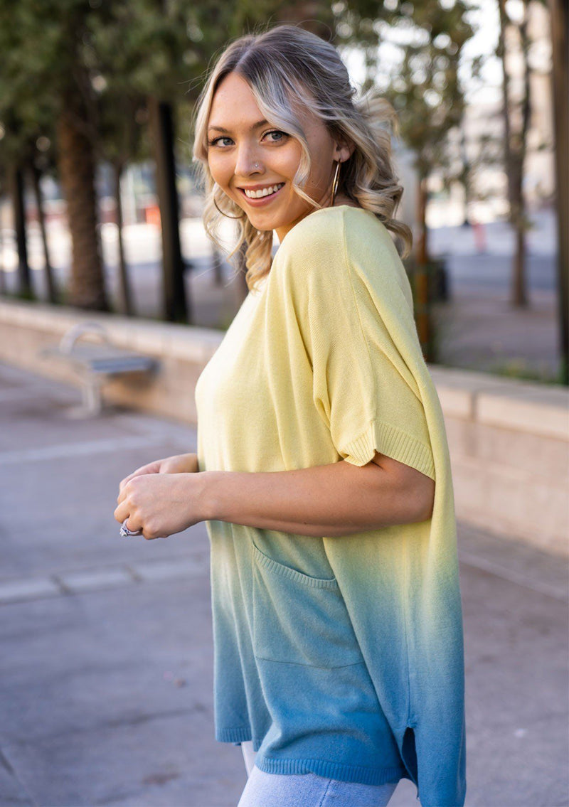 [Color: Lemon] A blond woman wearing an ombre tie dye sweater top. Features a scooped neckline, breezy side vents and front pockets. 