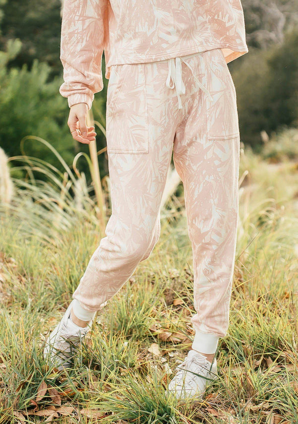 [Color: Blush/Natural] Girl wearing pink tropical print lounge jogger pants.