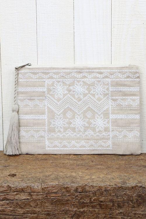 [Color: Natural] Image of a natural boho clutch featuring intricate embroidery, and a rope tassel zipper pull. .Crafted in a jute-blend with cotton lining. 