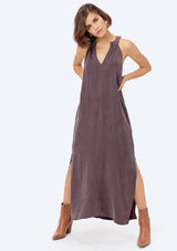 [Color: Charcoal] A brunette model wearing a cupro maxi dress with a split v-neckline, side pockets, and side slits. 