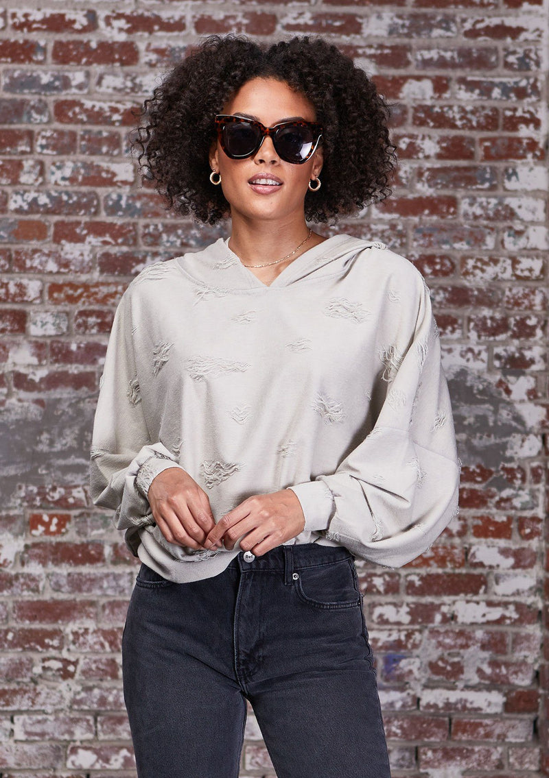 [Color: Stone] A soft lounge hooded sweatshirt featuring subtle distressed details, flattering dolman sleeves, and a slouchy hoodie. Styled here with jeans.