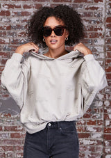 [Color: Stone] A soft lounge hooded sweatshirt featuring subtle distressed details, flattering dolman sleeves, and a slouchy hoodie. Styled here with jeans.