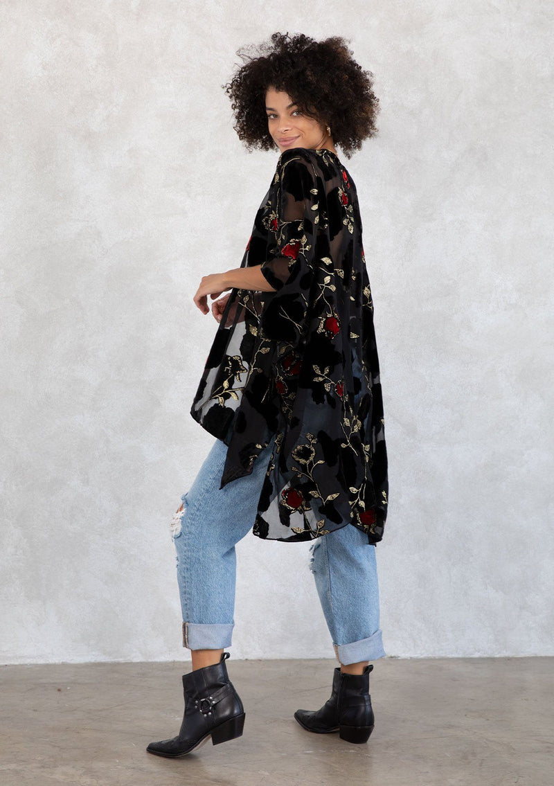 [Color: RedFloral/Black] A model wearing a holiday ready bohemian velvet kimono in black and red floral. With gold thread design, an open front, and half length sleeves. 