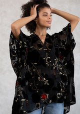 [Color: RedFloral/Black] A model wearing a holiday ready bohemian velvet kimono in black and red floral. With gold thread design, an open front, and half length sleeves. 