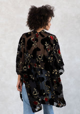 [Color: RedFloral/Black] A model wearing a holiday ready bohemian velvet kimono in black and red floral. With gold thread design, an open front, and half length sleeves. 