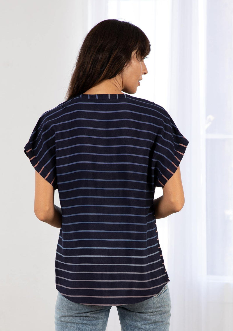 [Color: Navy/Blue] A model wearing a classic navy blue popover top in a gradient stripe print. Featuring a banded collar, short dolman sleeves with a folded cuff, and a sophisticated front pleat.