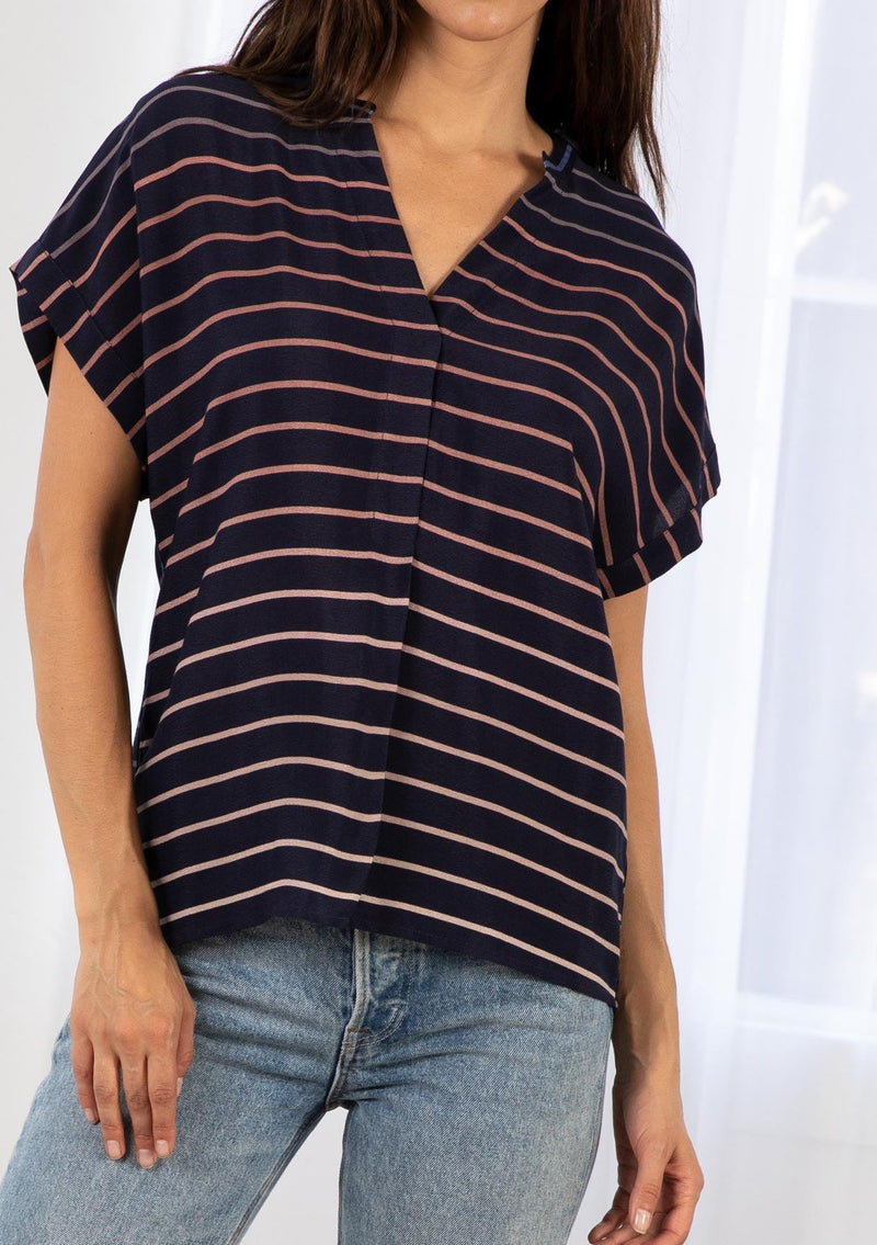 [Color: Navy/Blue] A model wearing a classic navy blue popover top in a gradient stripe print. Featuring a banded collar, short dolman sleeves with a folded cuff, and a sophisticated front pleat.