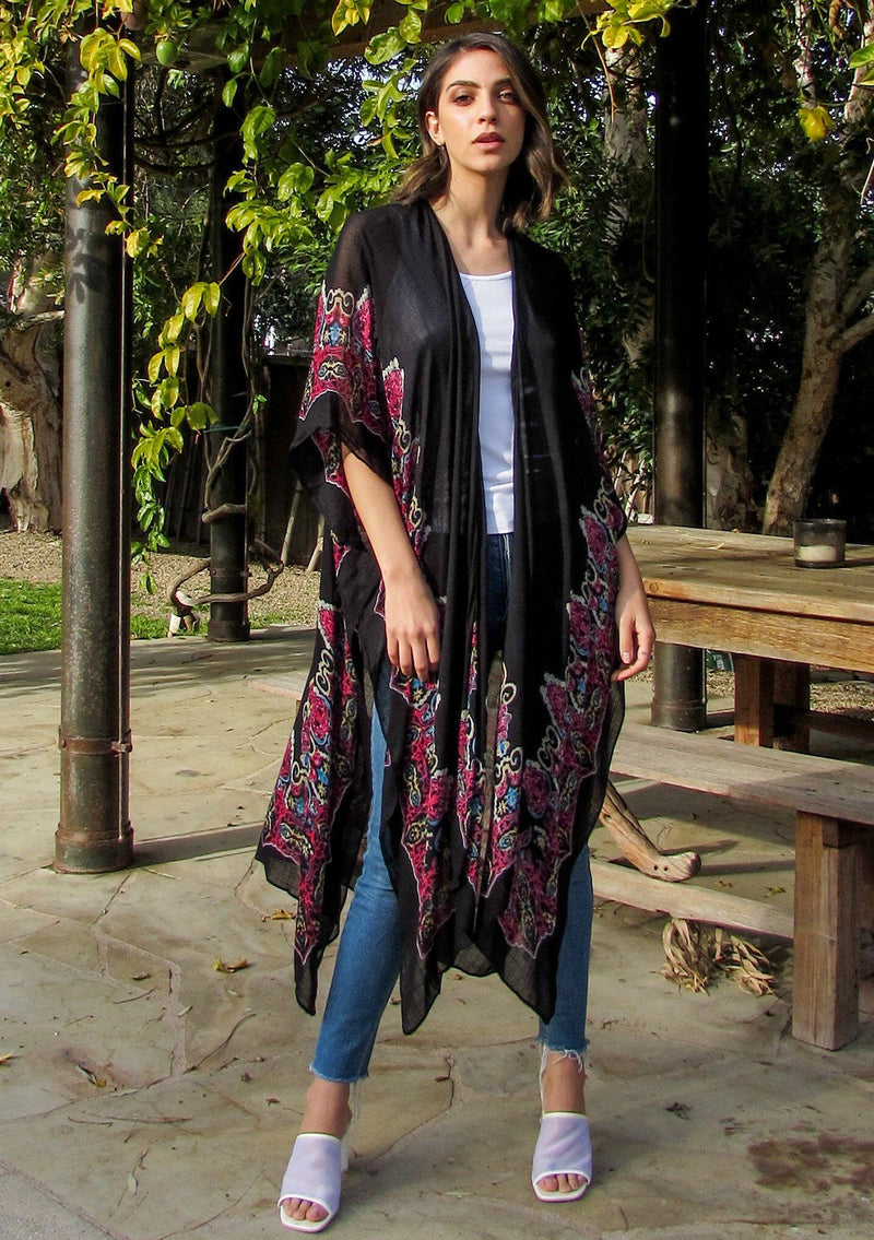 [Color: Black/Raspberry] A brunette woman standing poolside wearing a lightweight bohemian kimono. Featuring a medallion print design, half length kimono sleeves, side slits, and an open front.