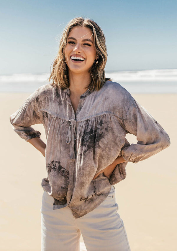 [Color: Cement] A classic peasant blouse in dreamy tie dye. Featuring voluminous three quarter length sleeves, a flattering v neckline, and a hidden button up front.