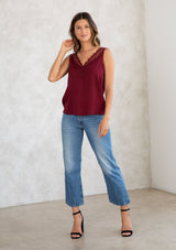 [Color: Merlot] A model wearing a merlot red camisole tank top. With a lace trim v neckline in front and back and a relaxed fit. 