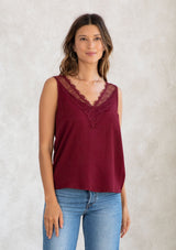 [Color: Merlot] A model wearing a merlot red camisole tank top. With a lace trim v neckline in front and back and a relaxed fit. 