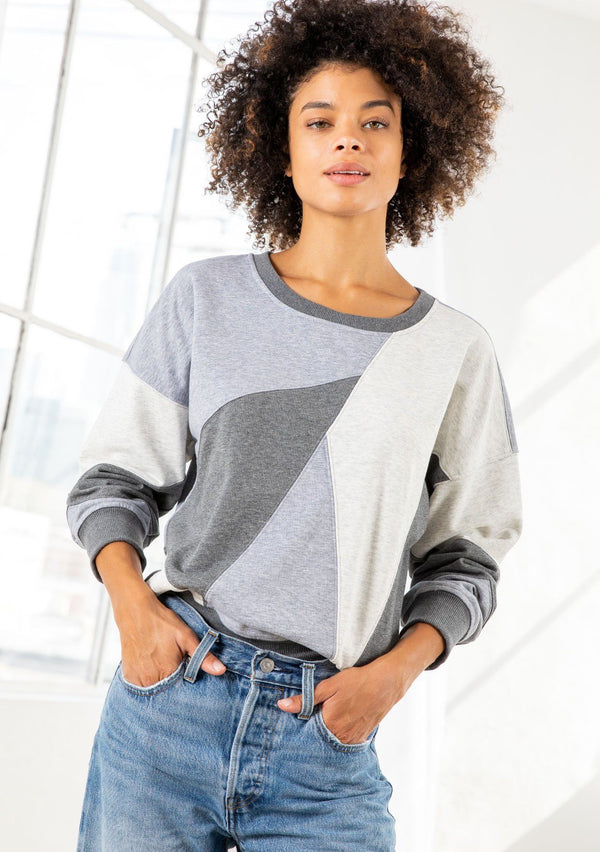 [Color: Heather Grey Combo] A model wearing a classic French terry sweatshirt in a trendy patchwork panel design. With a crew neckline and a contrast ribbed trim. 