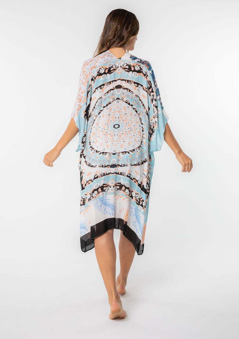 [Color: Lt Blue/Sand] A model wearing a stunning mid length kimono in a light blue mixed floral print. Featuring half length kimono sleeves, side slits, and an open front.